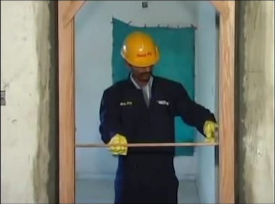Site worker checking a foam-fixed door frame for plumb