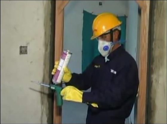 Site worker applying MULTIFOAM around a door frame with a dispenser gun